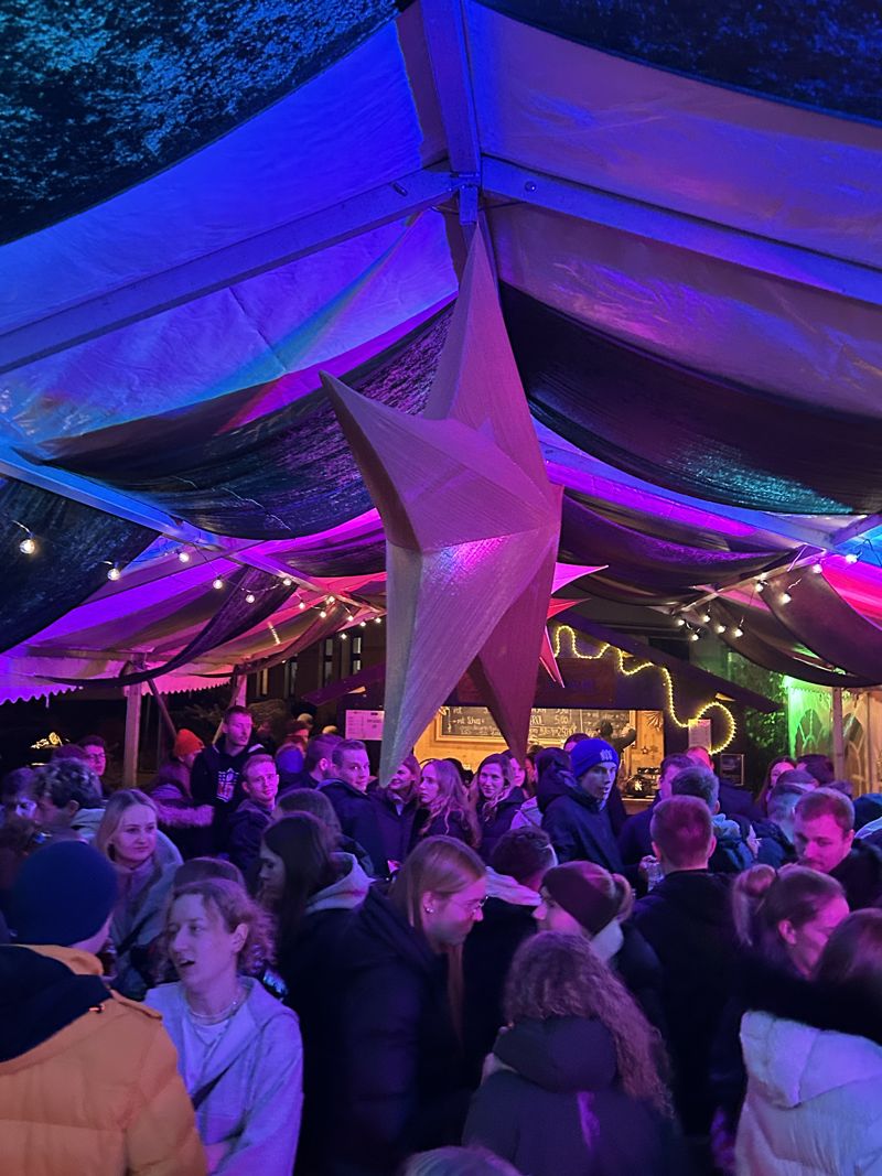 Volles Zelt mit großem Stern unter Lichterketten